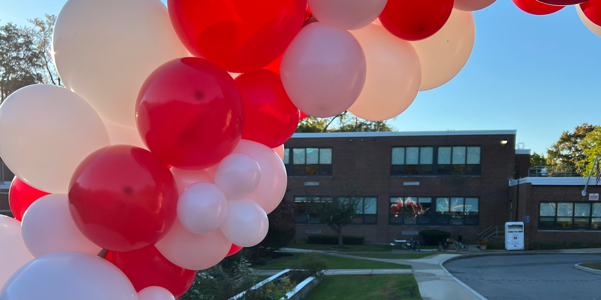 Red and white balloon arch with Hoover school in the background